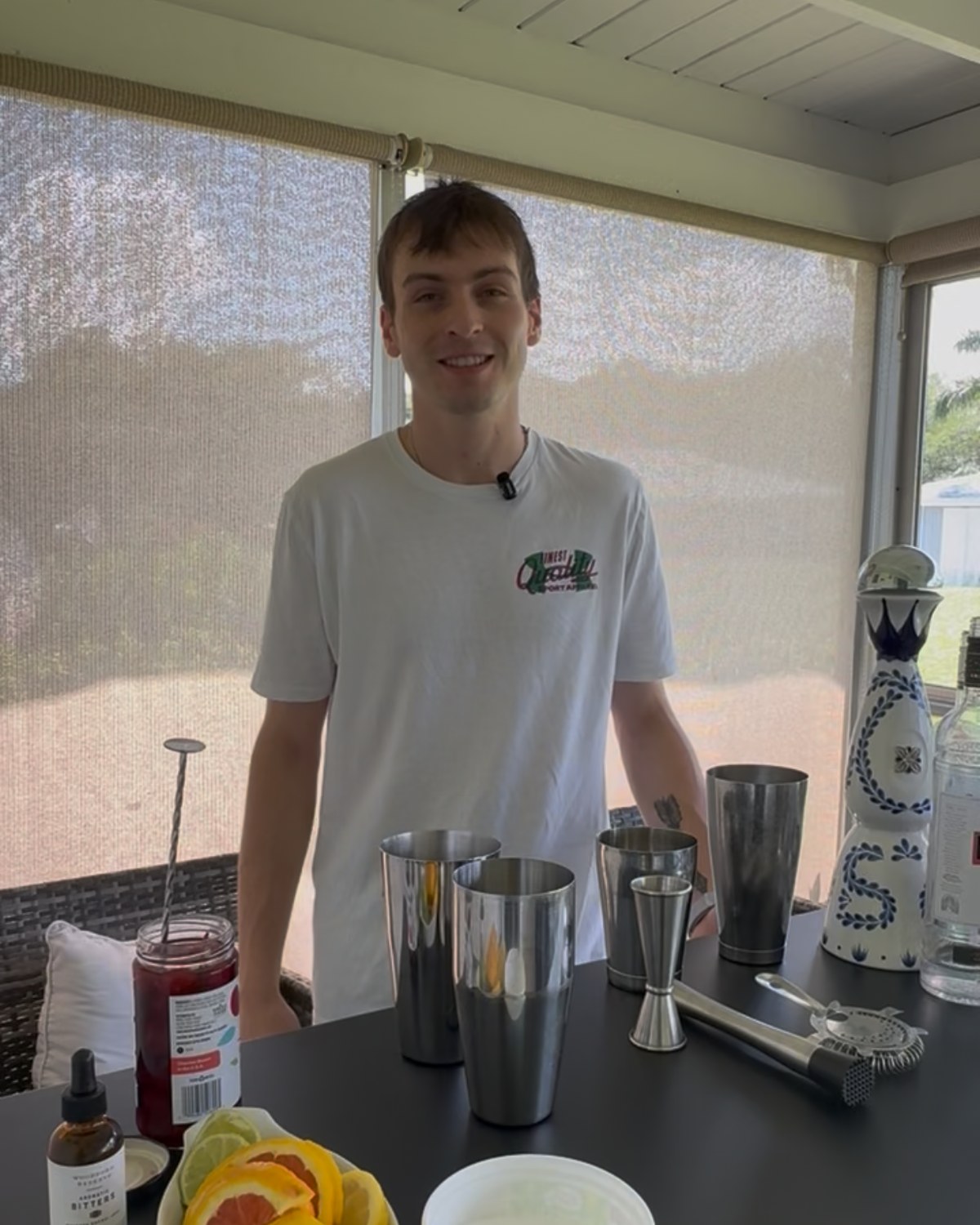 Steven Bell behind his mobile bar with shakers, jigger, and sliced citrus.