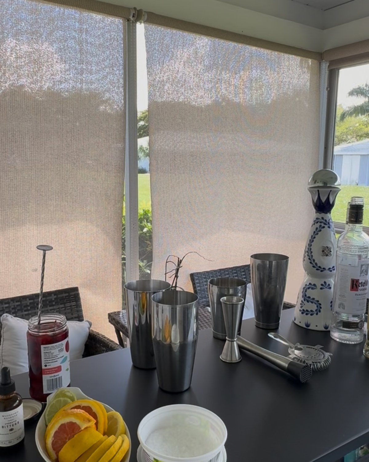 Shakers, jigger, strainer and sliced citrus laid out on a mobile bar.