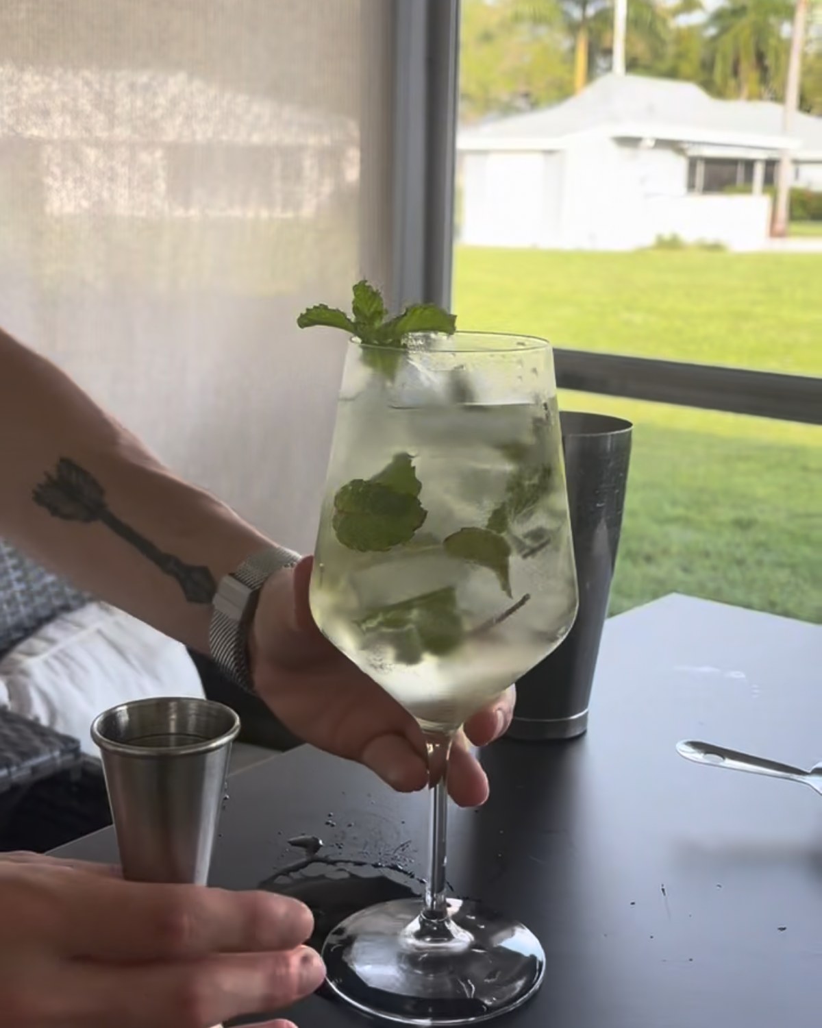 Mojito served in a stemmed glass, mint and lime over crushed ice.